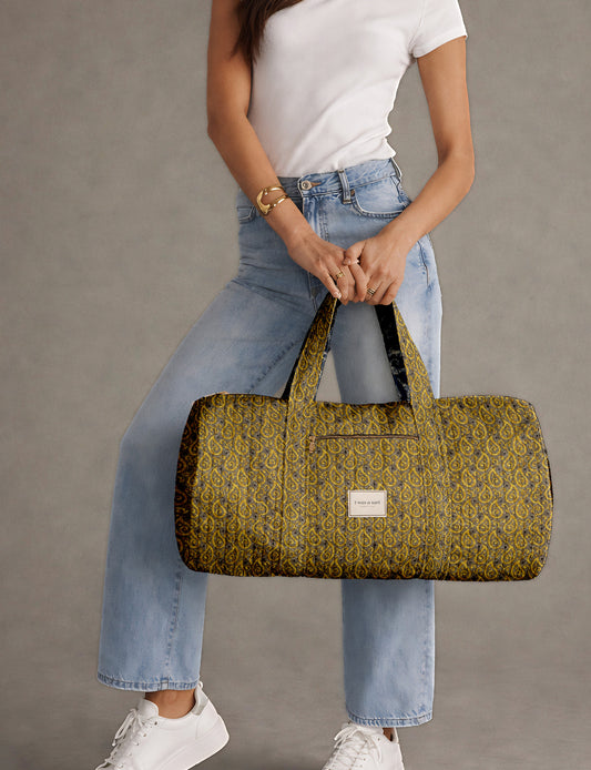 Brown paisley quilted bowling bag with dual handles, front zipper pocket, and "I was a sari" label on front side