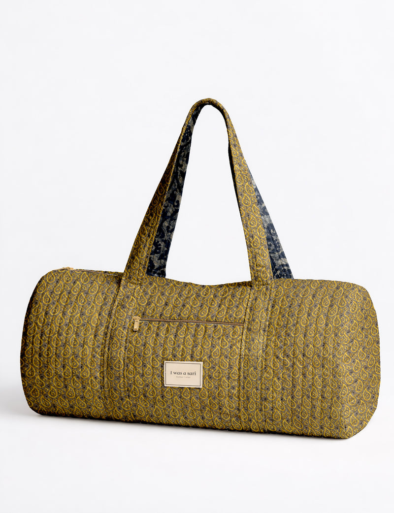 Brown paisley quilted bowling bag with dual handles, front zipper pocket, and "I was a sari" label on front side