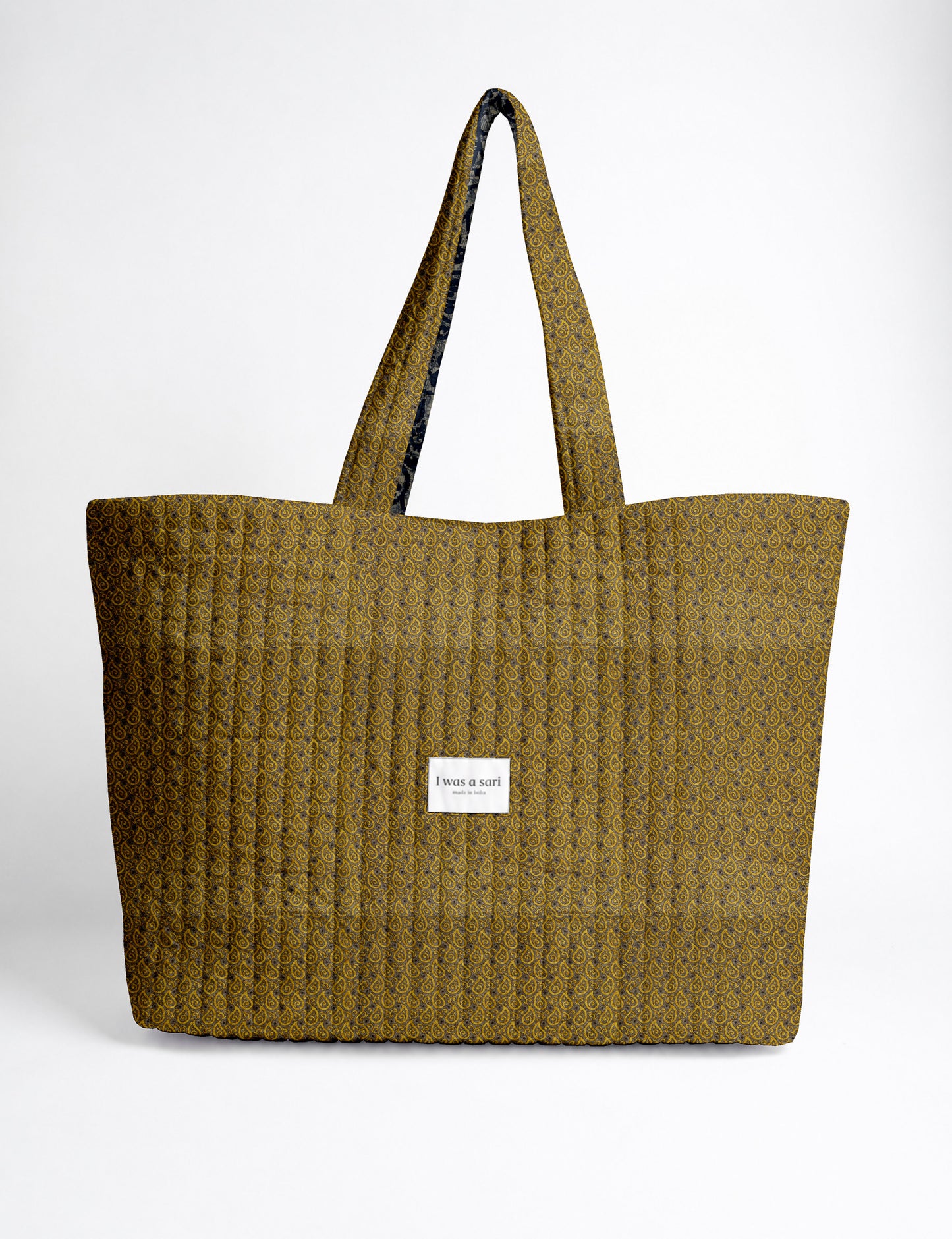 Quilted yellow tropical patterned beach bag with long handles and white label reading "I was a sari" front view