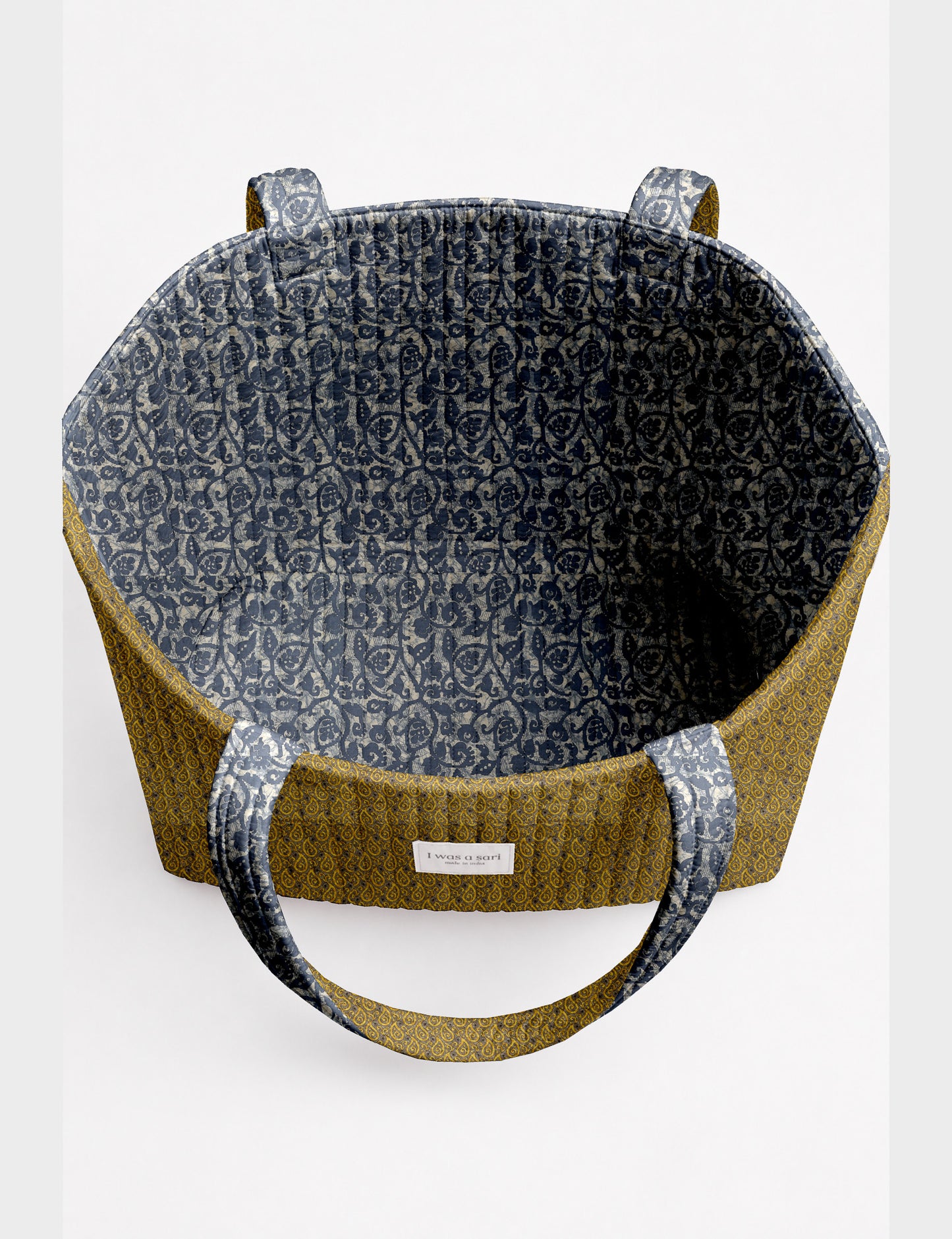 Quilted beach bag with yellow tropical exterior and red patterned interior, shown from top view with handles visible