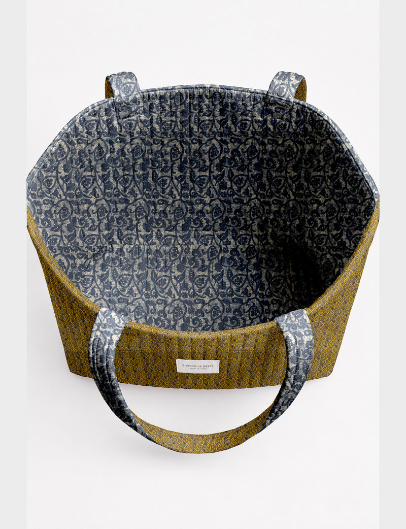 Quilted beach bag with yellow tropical exterior and red patterned interior, shown from top view with handles visible