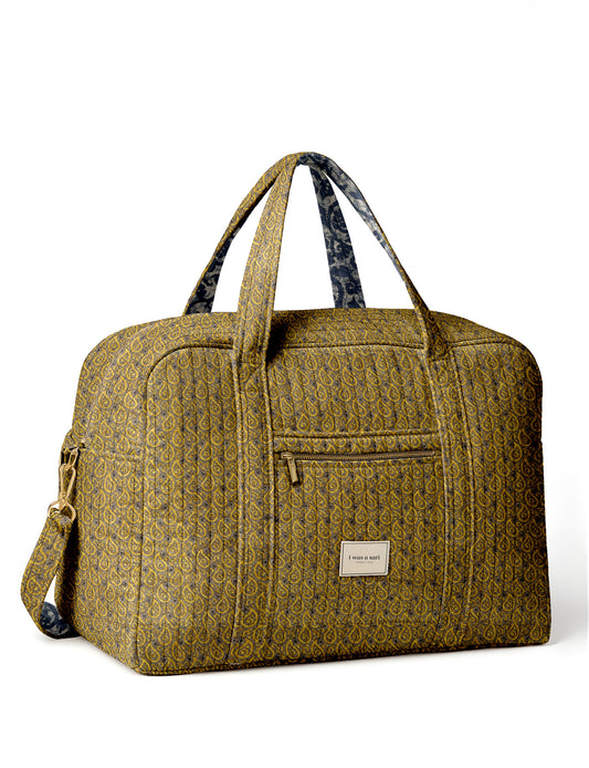 Brown quilted duffle bag with paisley pattern, front zip pocket, dual handles, and label reading "I was a sari"