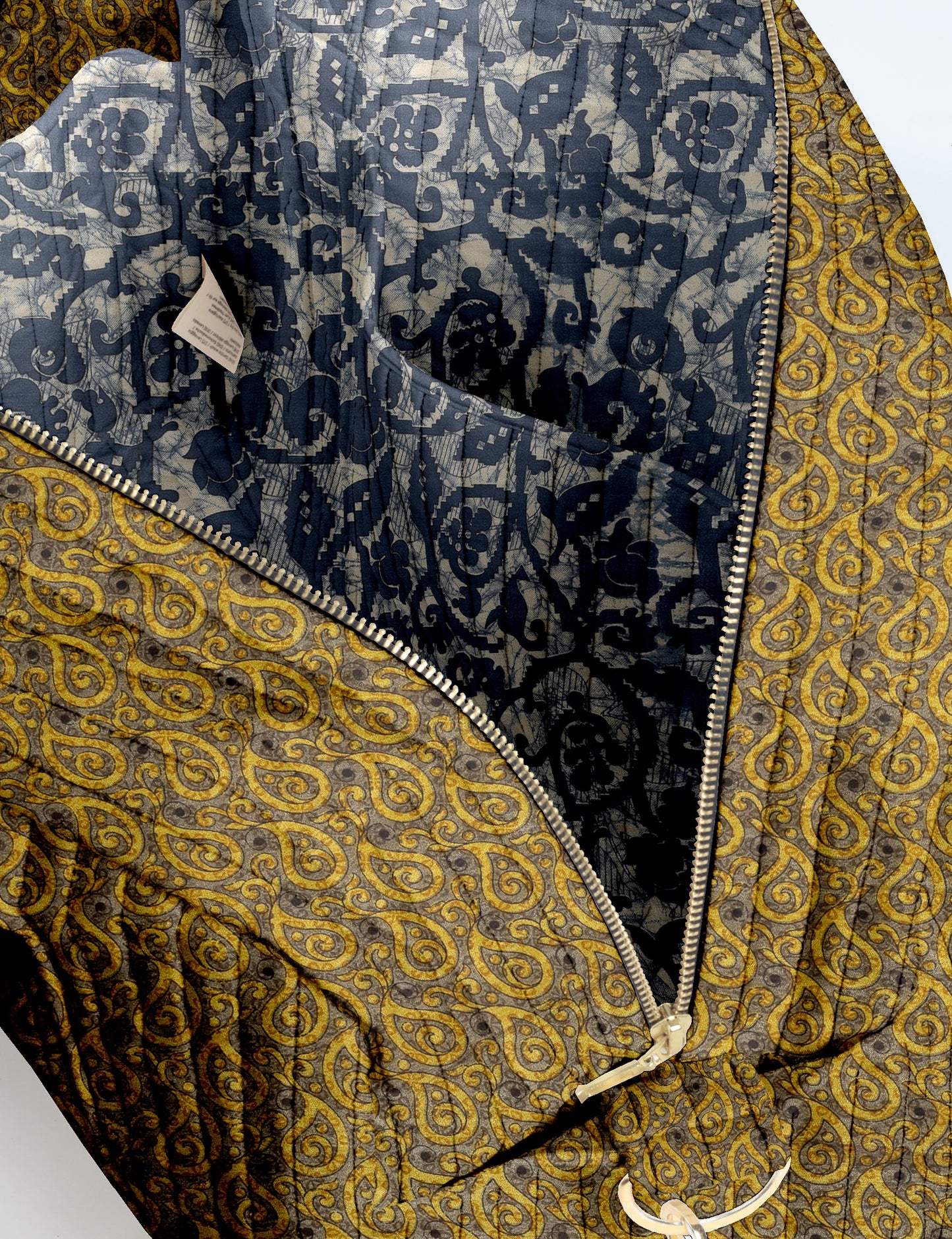 Brown quilted duffle bag with paisley pattern, front zip pocket, dual handles, and label reading "I was a sari"