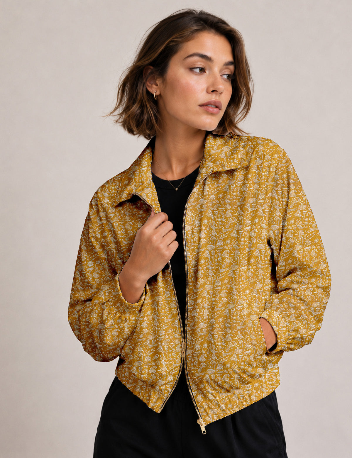 Woman wearing a yellow floral bomber jacket with front zipper, elastic cuffs, and side pockets, shown from front view