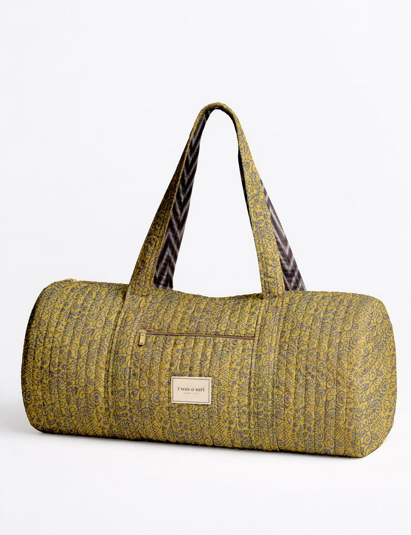 Yellow tropical patterned quilted bowling bag with dual handles, front zipper pocket, and "I was a sari" label on front side