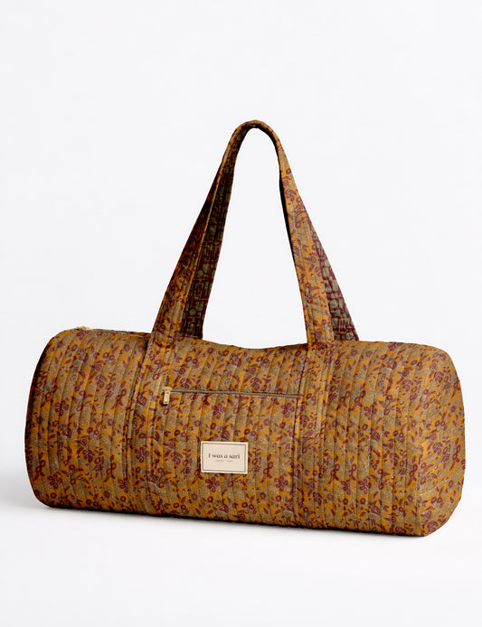 Beige quilted bowling bag with micro floral pattern, front zipper pocket, and dual handles with striped inner lining