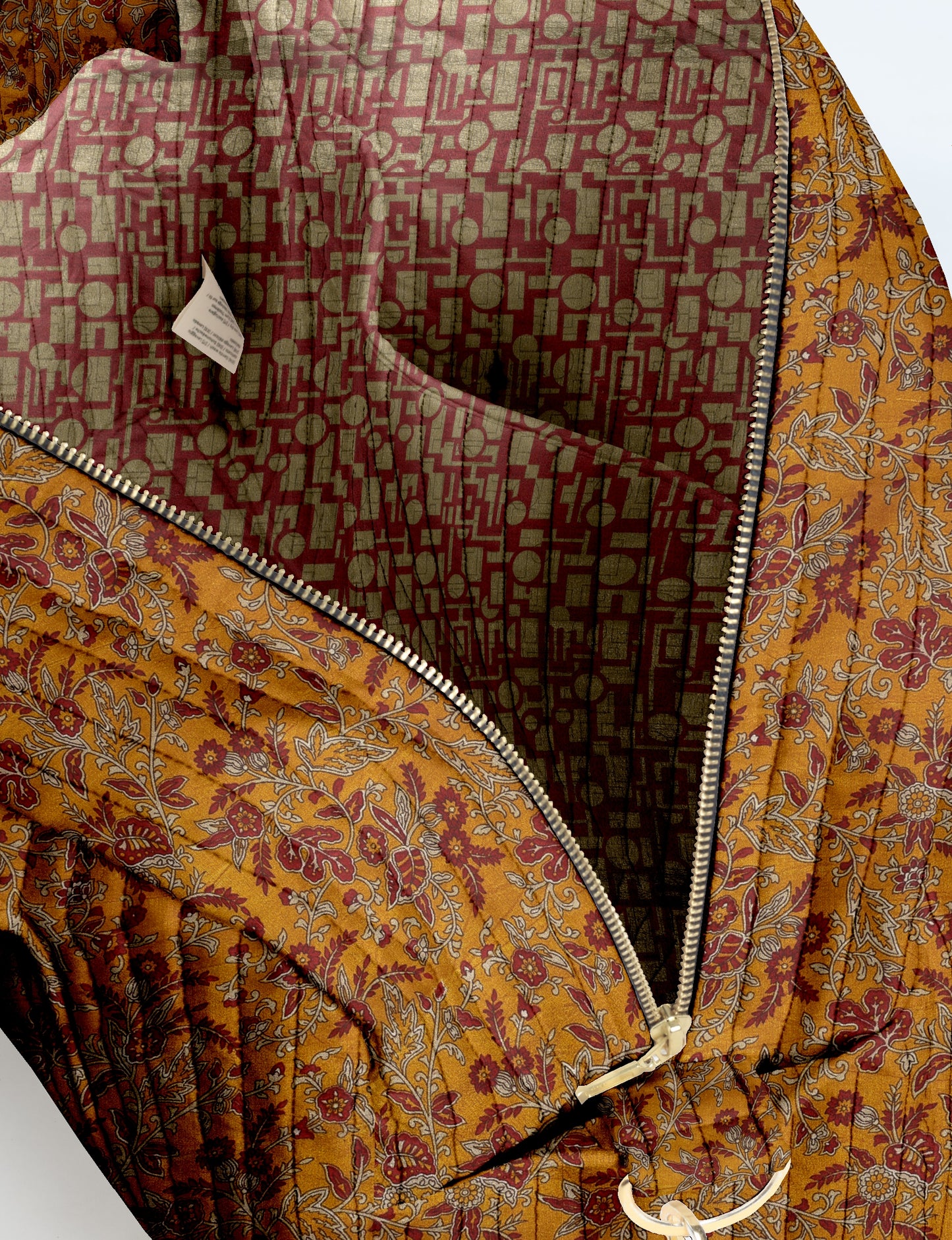 Quilted duffle bag with yellow floral tropical print exterior and red geometric patterned interior, open zipper view
