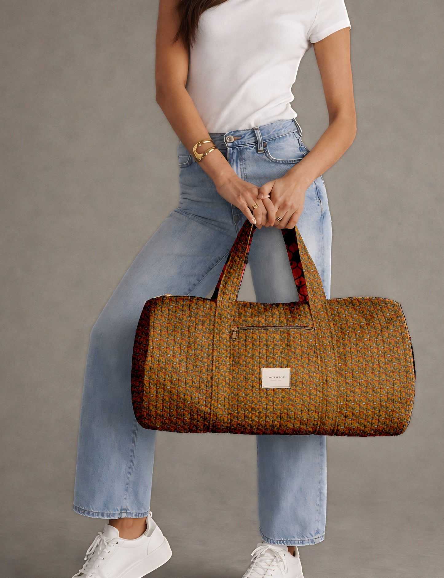 Beige quilted bowling bag with micro floral print exterior and blue geometric patterned interior, open zipper view