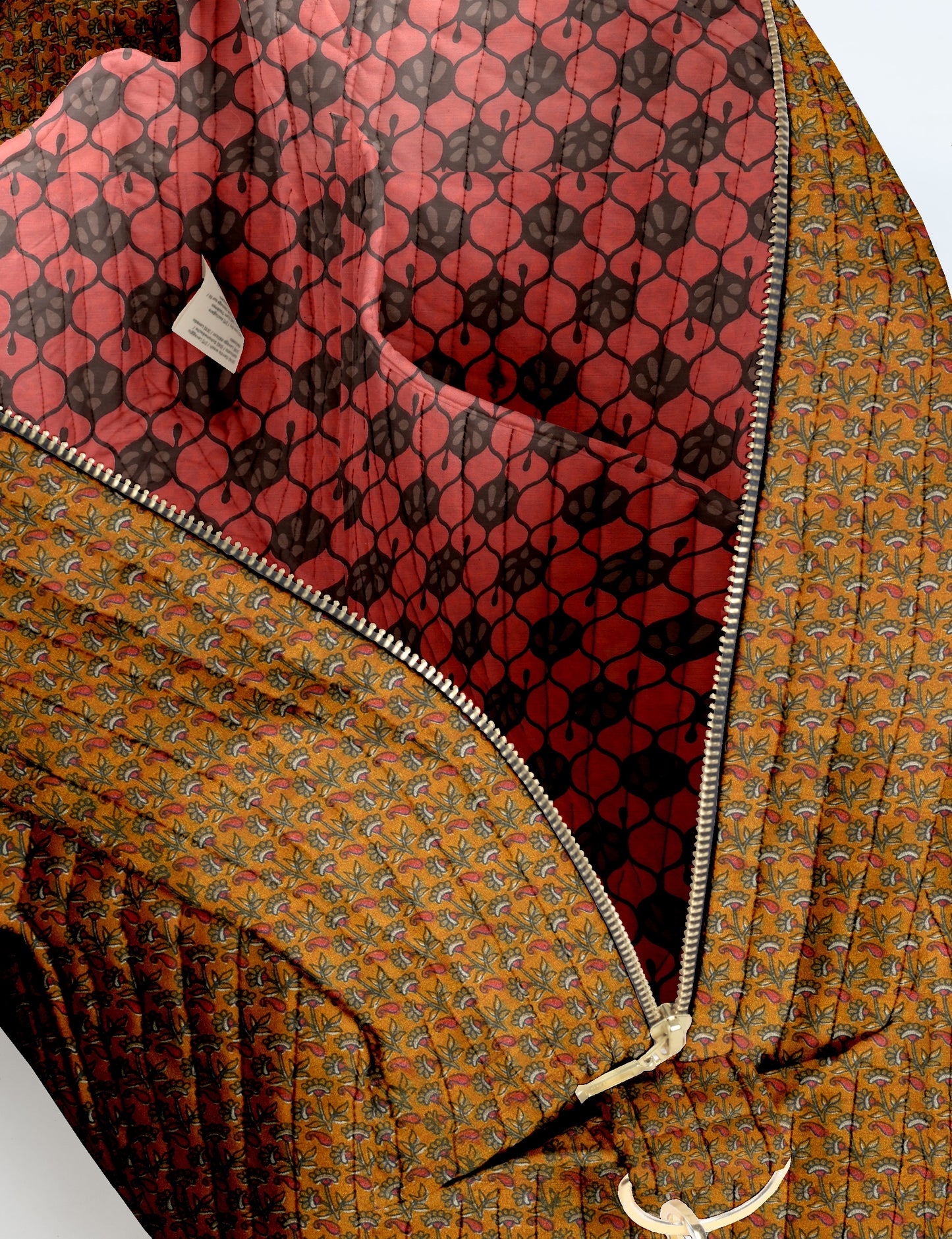 Quilted duffle bag with yellow floral exterior, red and black patterned interior, and silver zipper closure