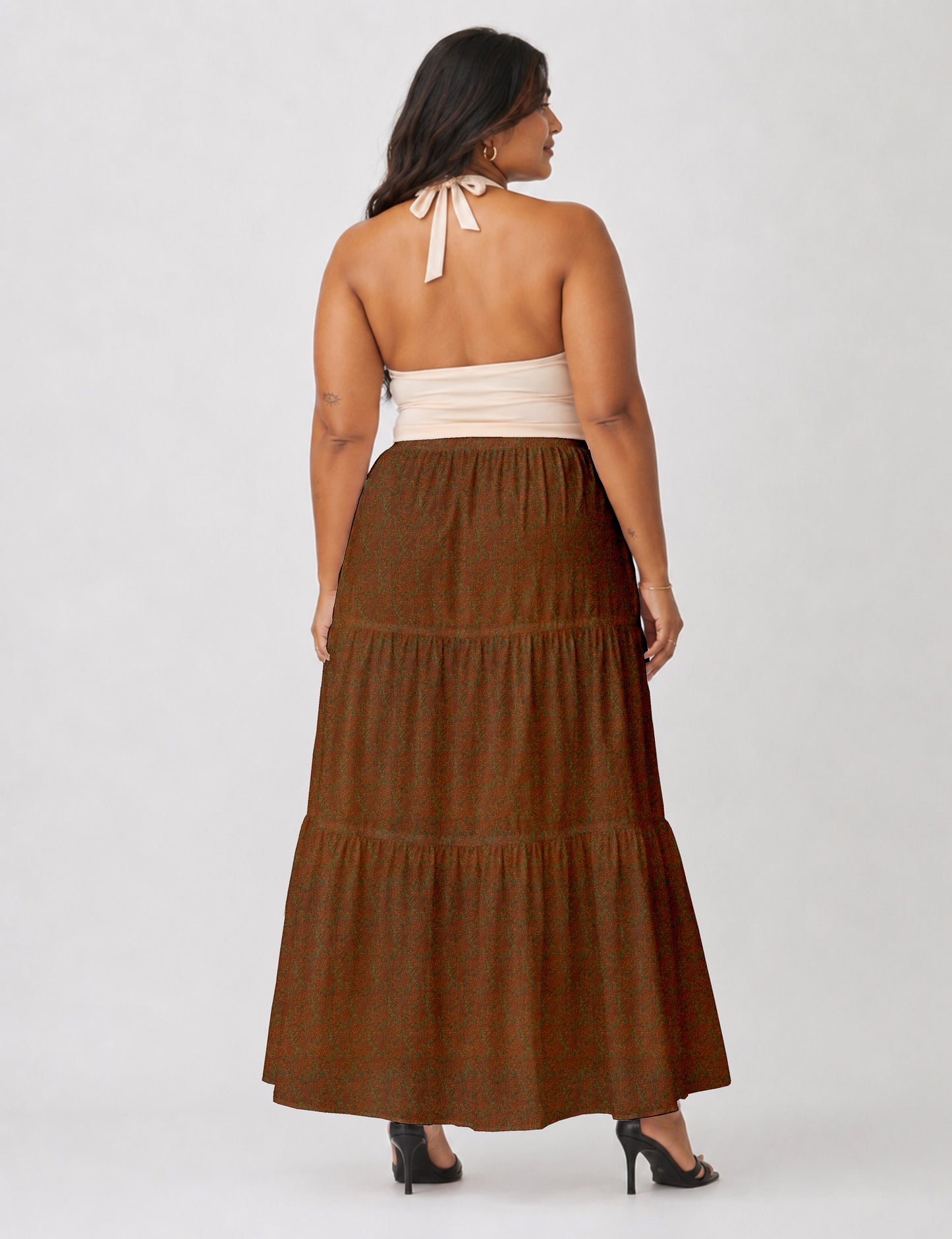 Woman wearing a yellow midi tiered skirt with a small geometric pattern, shown from the back, paired with beige top and