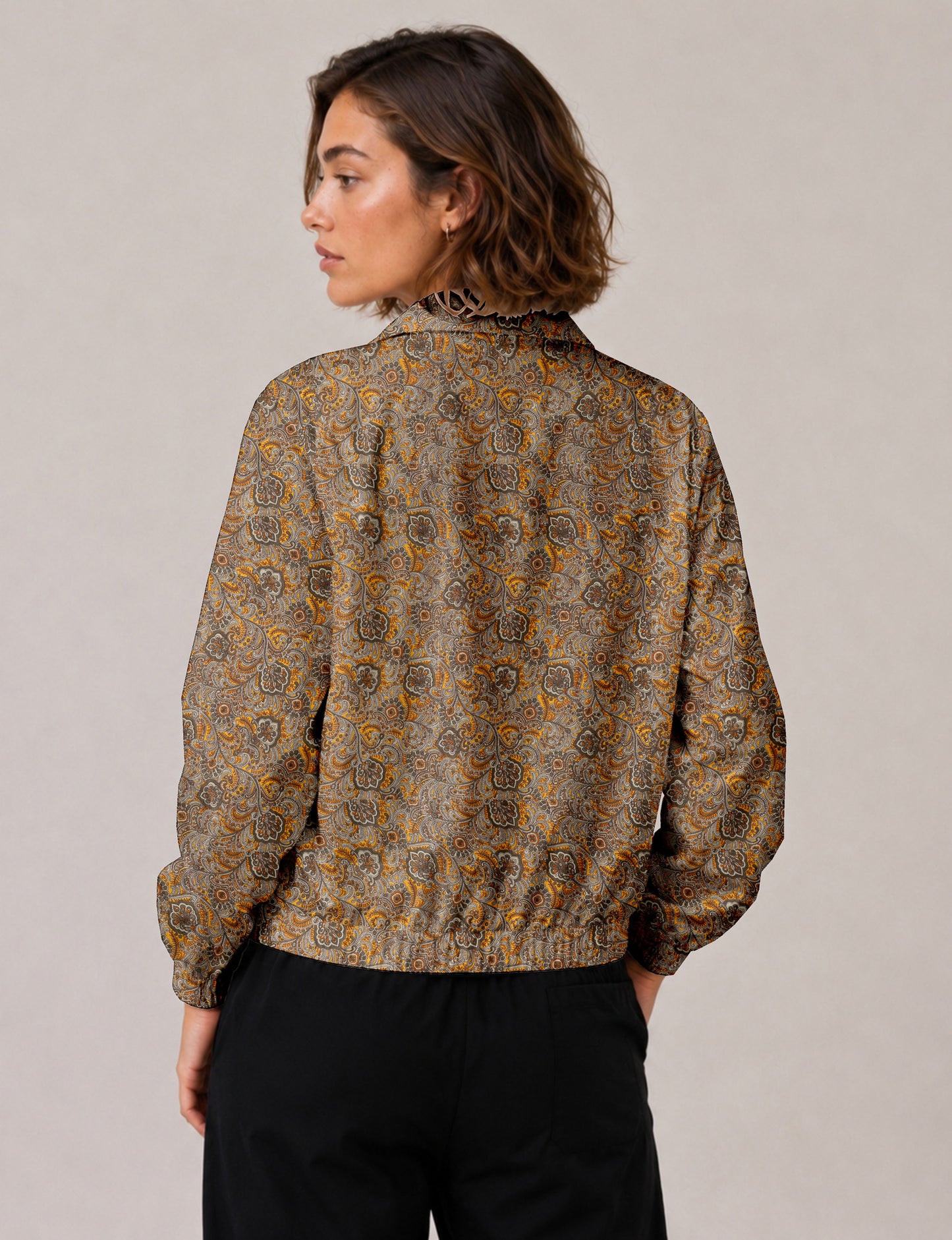 Woman wearing a yellow floral bomber jacket with front zipper, elastic cuffs, and side pockets, shown from front view
