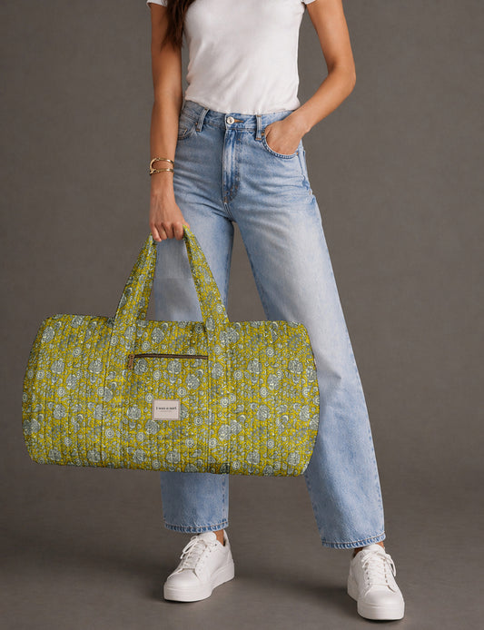Quilted brown paisley barrel bag with double handles, front pocket, and gold zipper, shown in side angle view