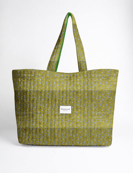Quilted yellow tropical patterned beach bag with long handles and white label reading "I was a sari" front view