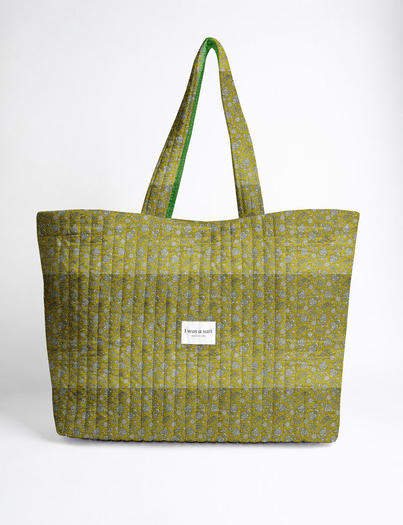 Quilted yellow tropical patterned beach bag with long handles and white label reading "I was a sari" front view