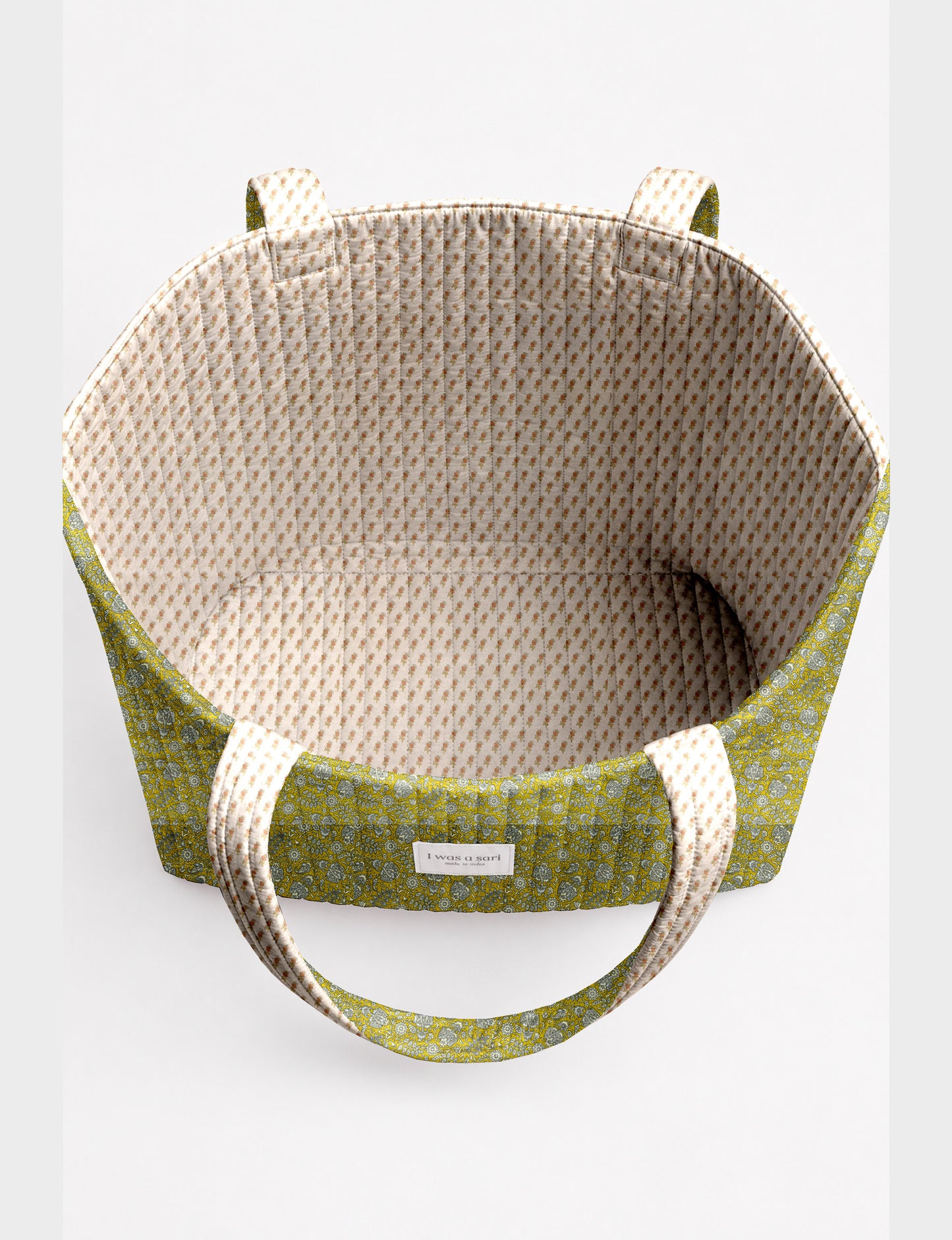 Quilted beach bag with yellow tropical exterior and red patterned interior, shown from top view with handles visible