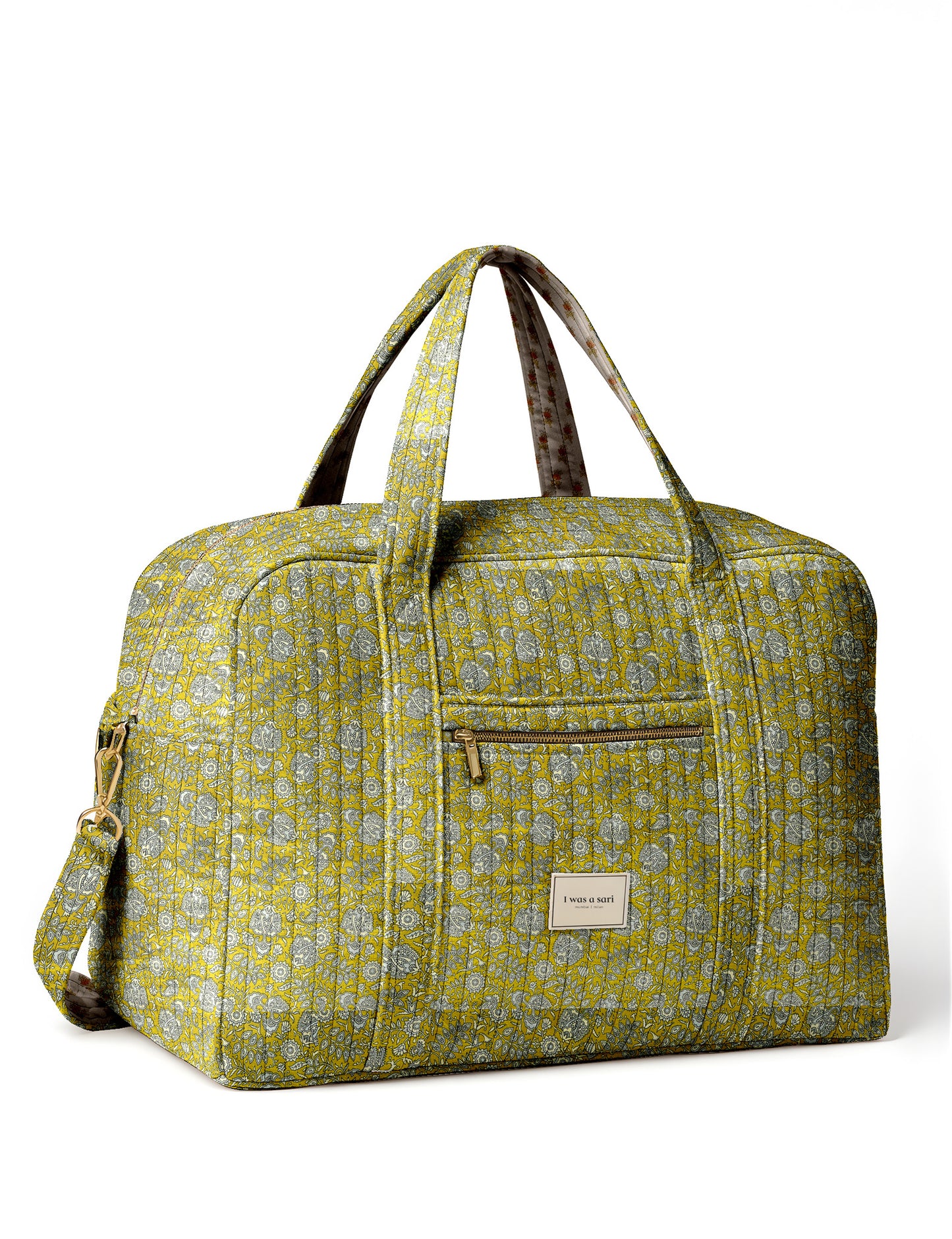Brown quilted duffle bag with paisley pattern, front zip pocket, dual handles, and label reading "I was a sari"