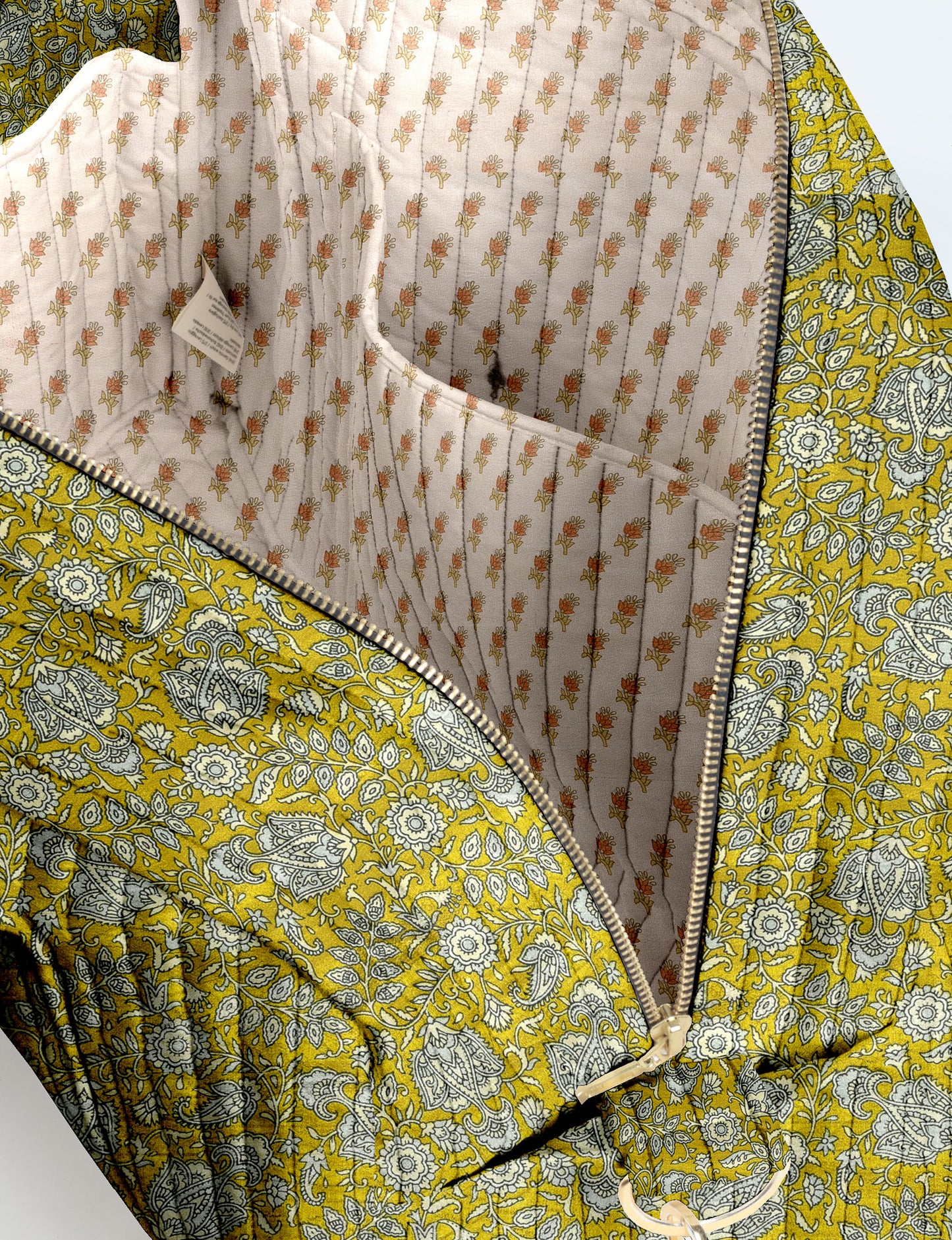Brown quilted duffle bag with paisley pattern, front zip pocket, dual handles, and label reading "I was a sari"