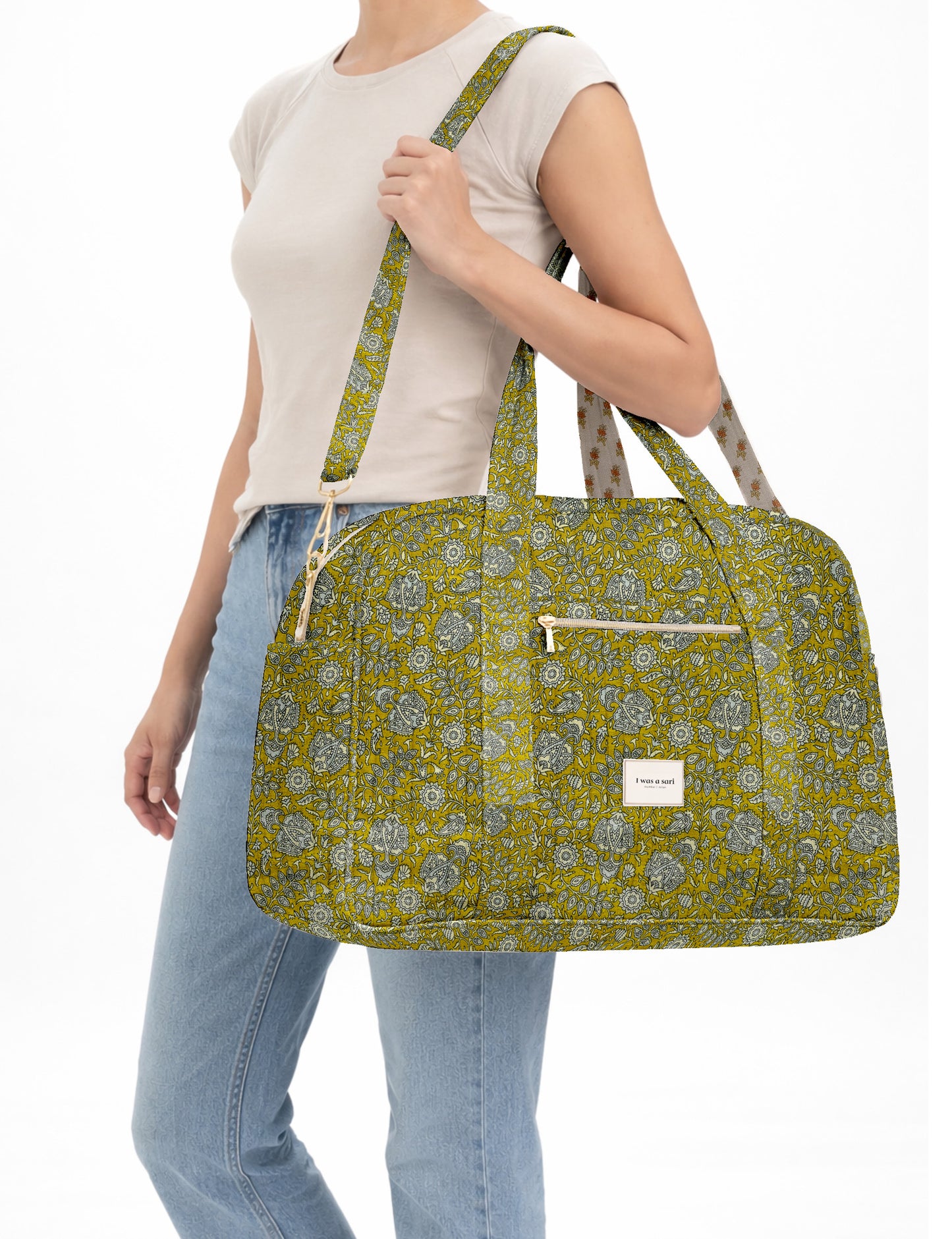 Brown quilted duffle bag with paisley pattern, front zip pocket, dual handles, and label reading "I was a sari"