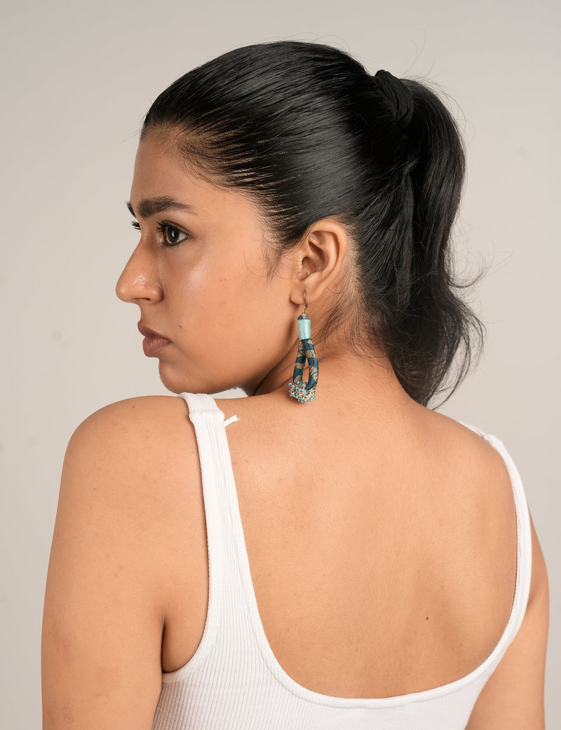 Model wearing blue and black patterned beaded drop earrings with small bead clusters, side profile view on neutral background