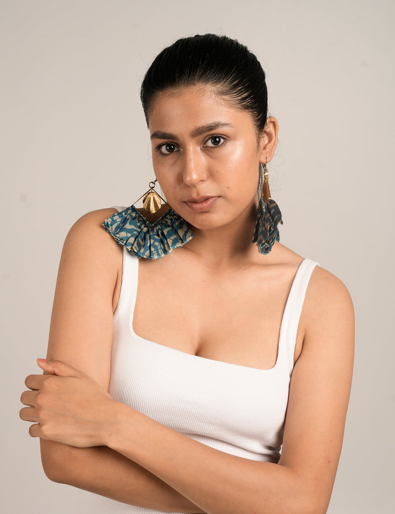 Model wearing maxi square earrings with blue floral fabric and gold metal shell detail, front view, white tank top