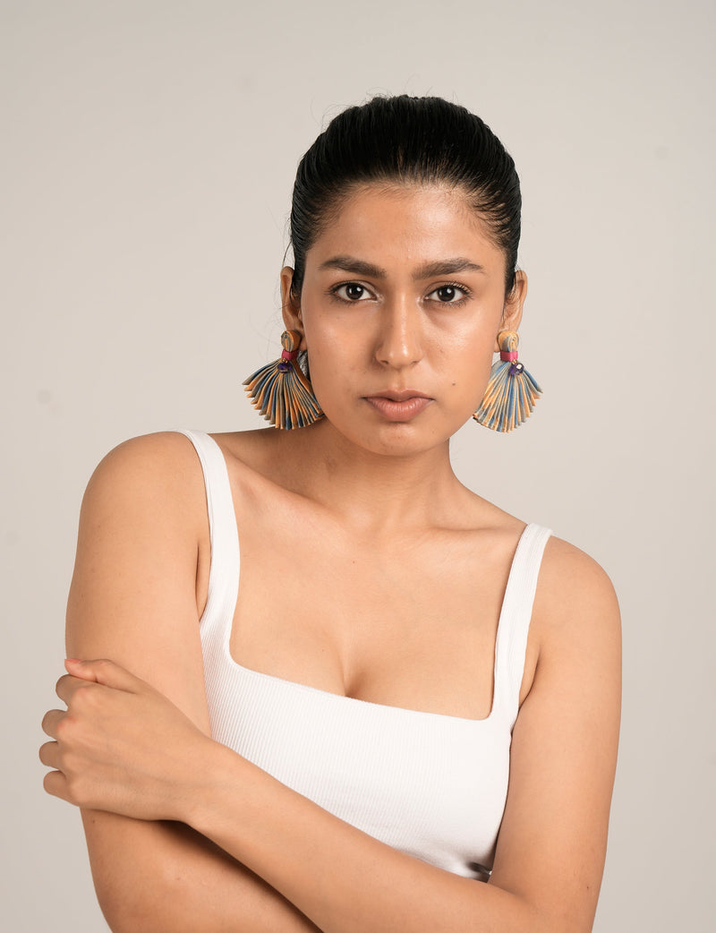 Model wearing beige abstract pleated fan-shaped earrings with blue and orange accents, front view, close-up