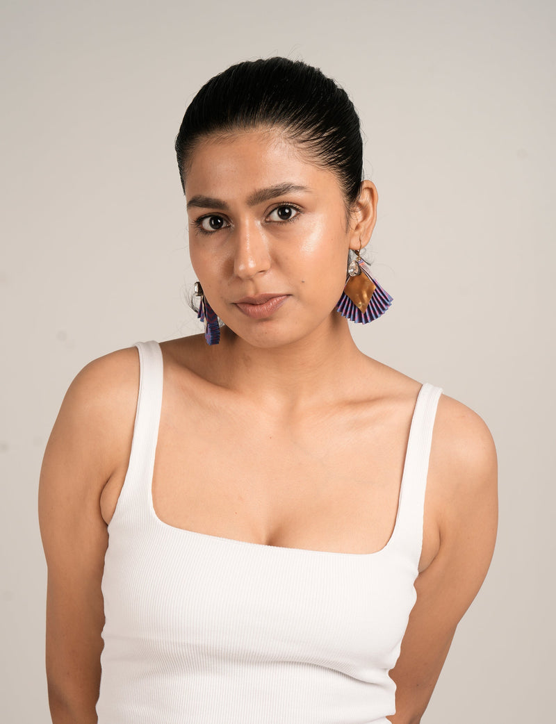 Model wearing pleated earrings with blue and purple abstract pattern, gold diamond-shaped detail, and clear bead accents