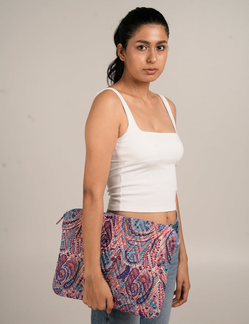 Quilted laptop sleeve in blue floral pattern held by a woman wearing a white tank top and blue jeans