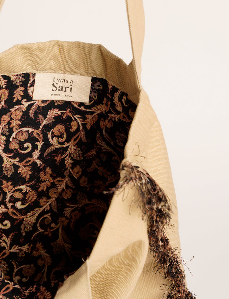 Beige fabric shopper bag with black floral patterned interior lining and a label reading "I was a Sari mumbai | milan"
