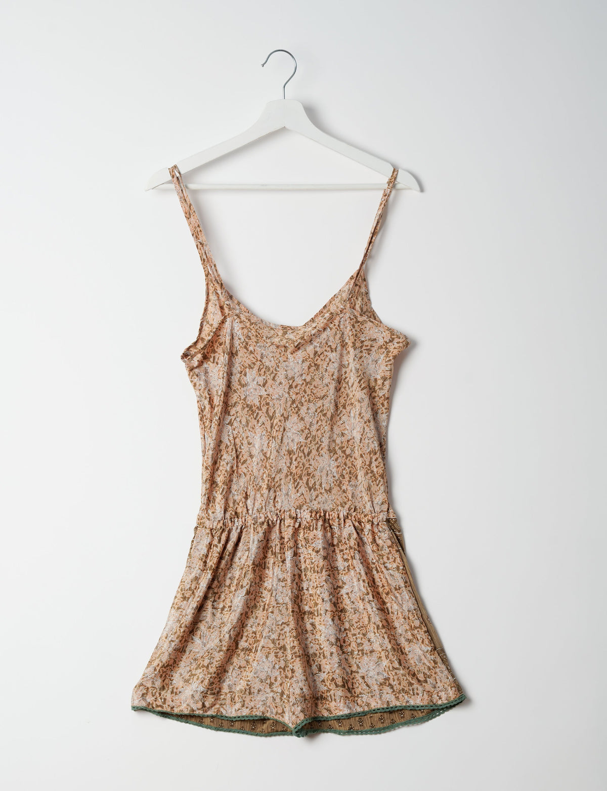 Beige floral playsuit with lace trim at hem, adjustable spaghetti straps, and gathered waist, hanging on white hanger